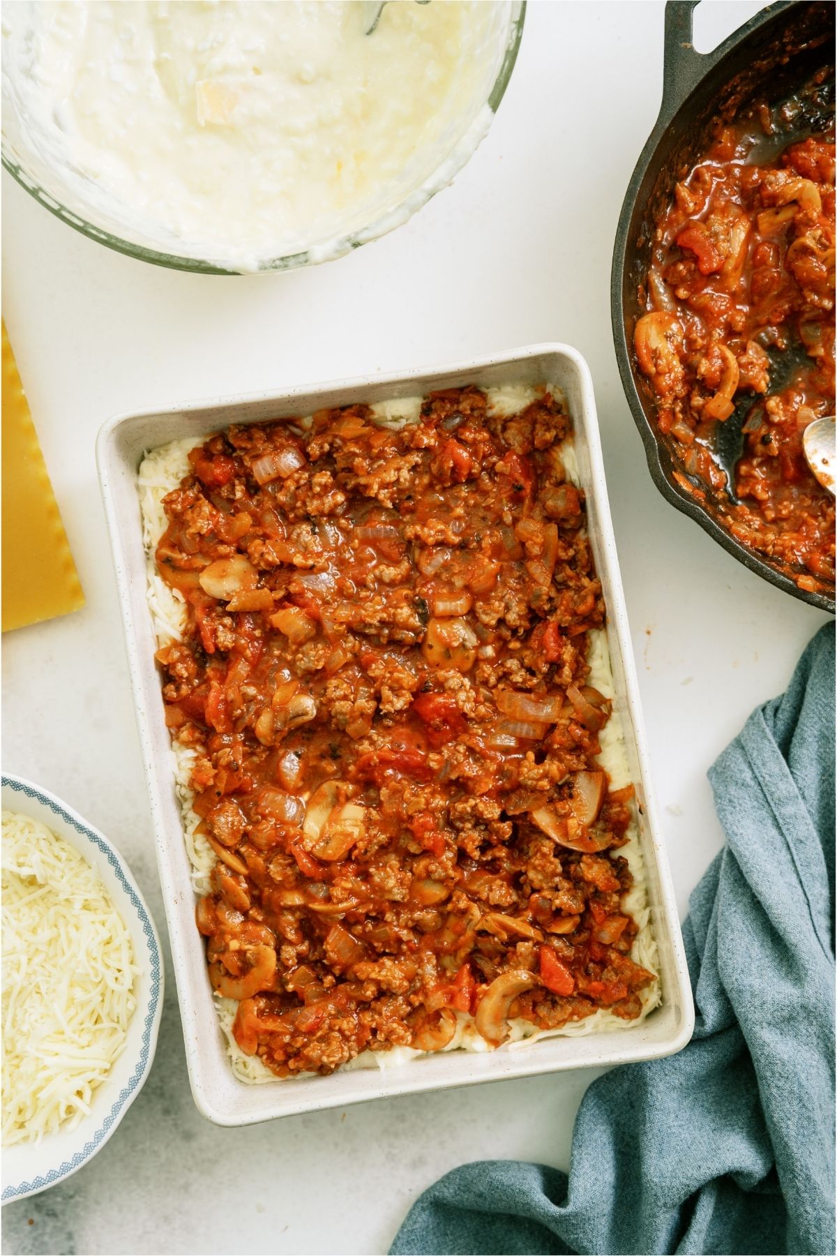 Meat sauce layered over cheese layer in dish.