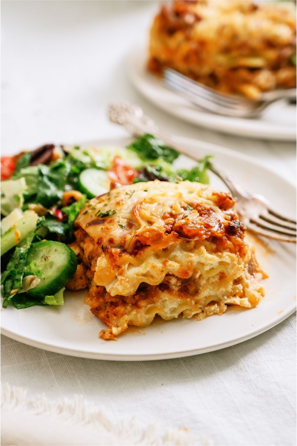A slice of Easy Homemade Lasagna on a plate with salad.
