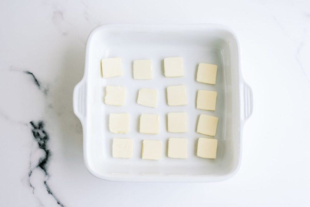 Squares of butter placed in an 8x8 baking dish.