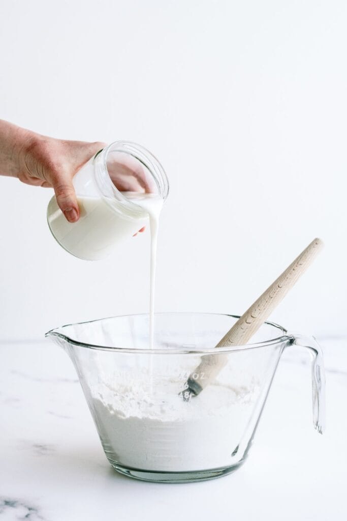Adding buttermilk to flour mixture in mixing bowl.