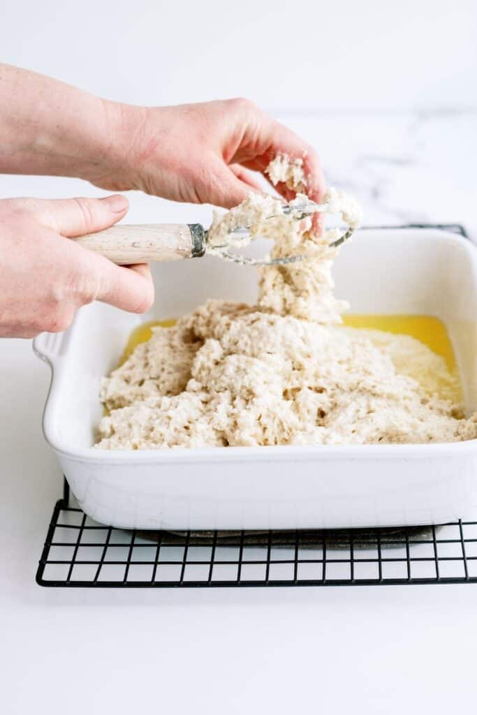 Placing biscuit dough in baking dish with melted butter.