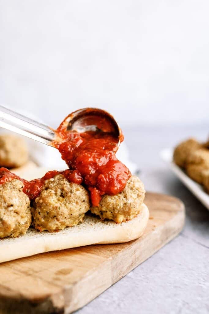 Scooping sauce on top of a Homemade Turkey Meatball Sub.