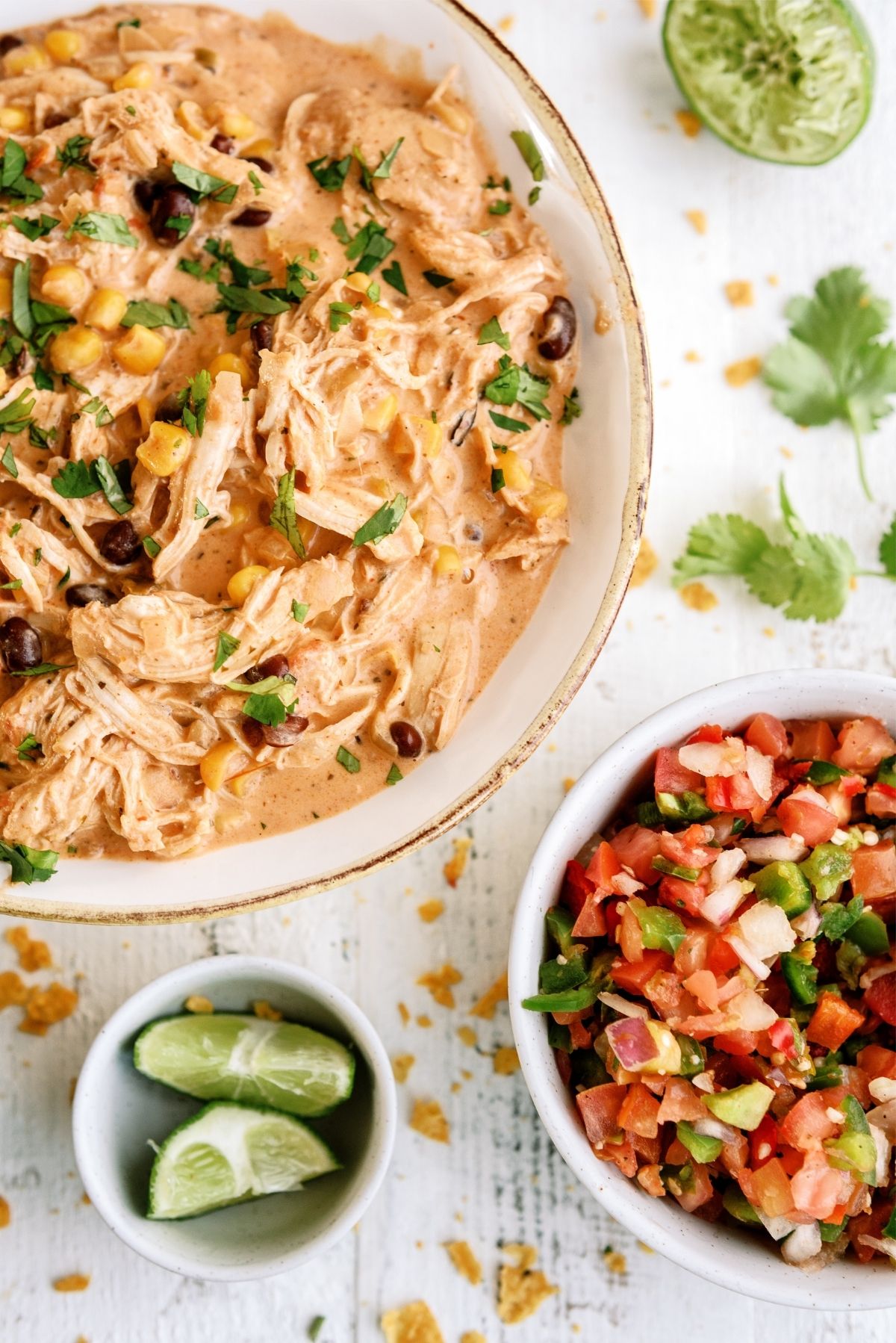 Instant Pot Creamy Fiesta Chicken in a bowl with a bowl of pico and a bowl of limes on the side