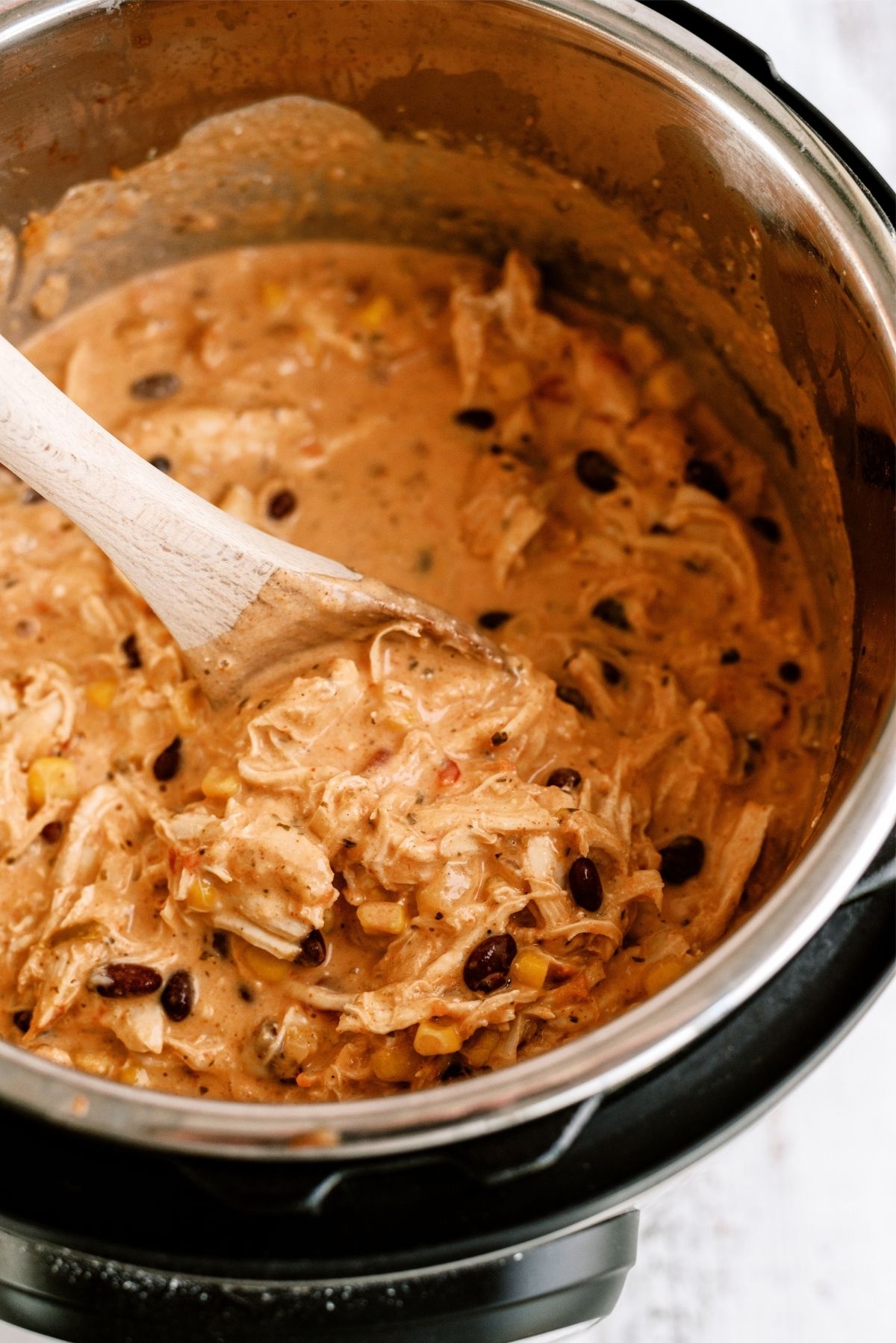 Instant Pot Creamy Fiesta Chicken in the instant pot with a wooden spoon