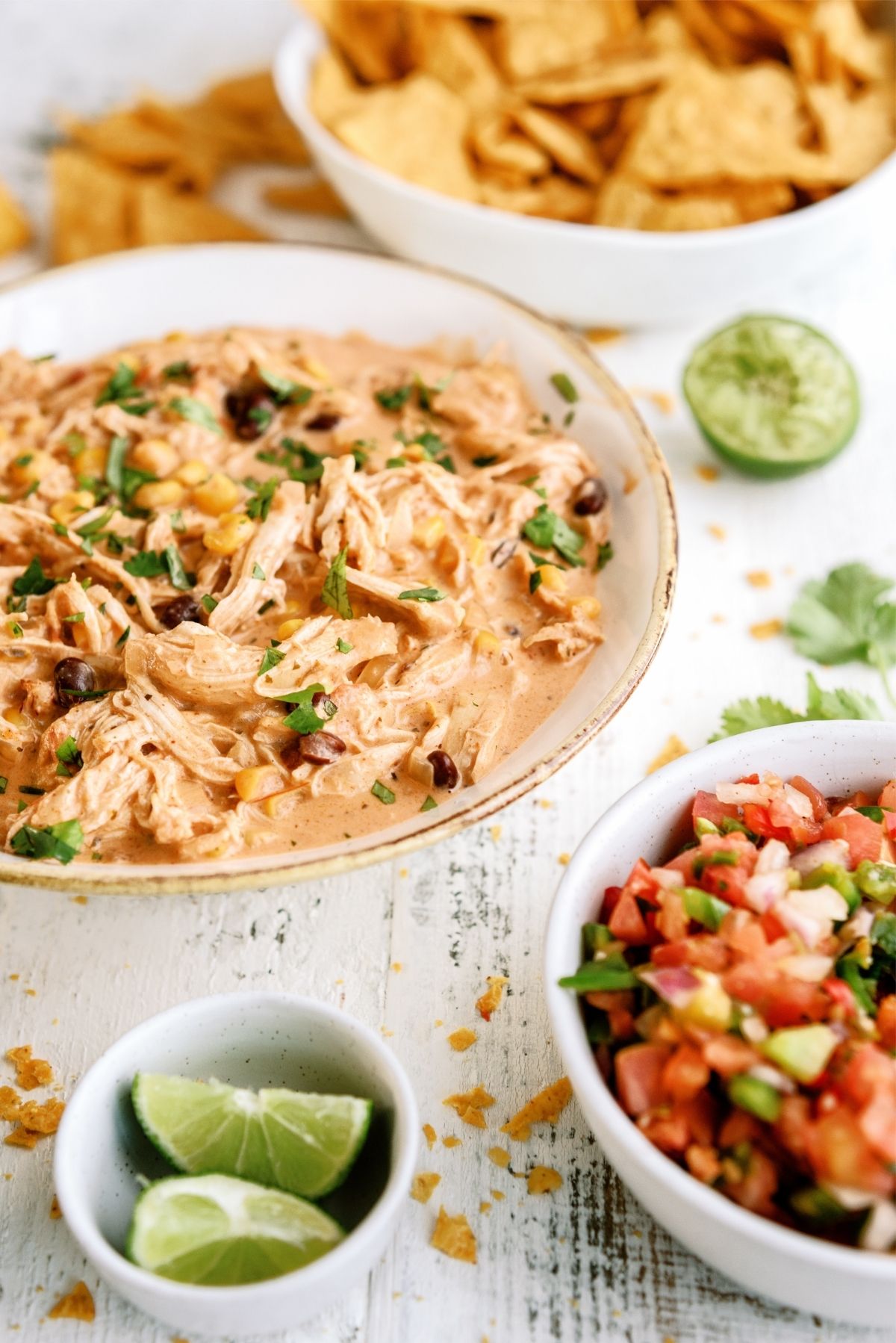 Instant Pot Creamy Fiesta Chicken in a bowl with chips, pico and limes on the side
