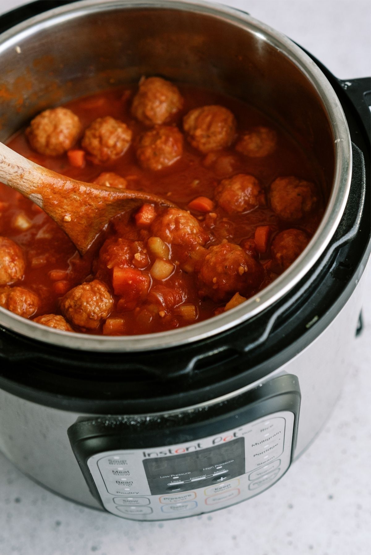 Instant Pot Dump and Go Meatball Soup in the instant pot with a wooden spoon