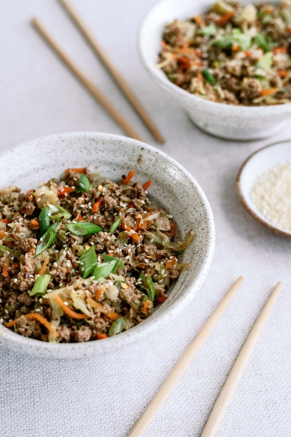 Instant Pot Egg Roll Bowls in 2 bowls with chopsticks and sauce on the side