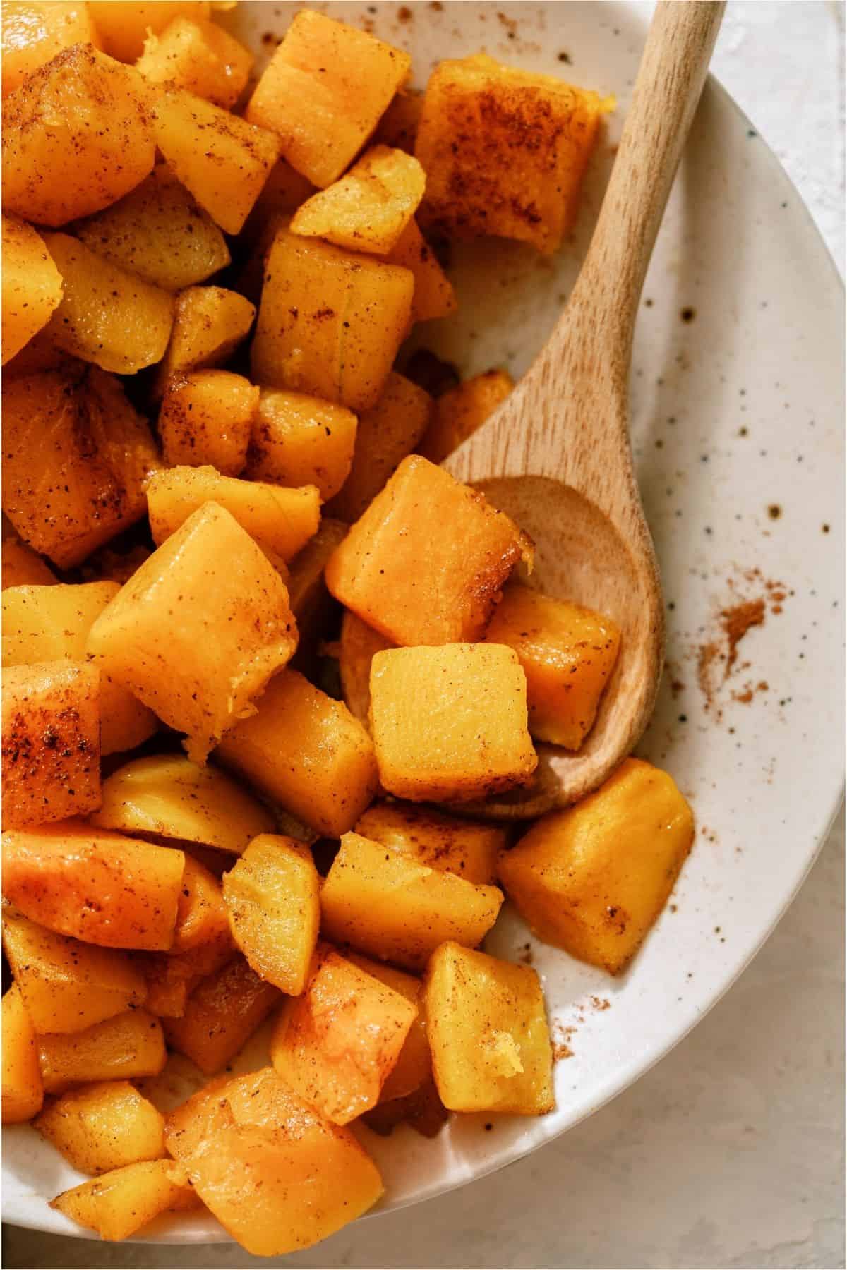 Maple Roasted Butternut Squash in a bowl with a wooden spoon.