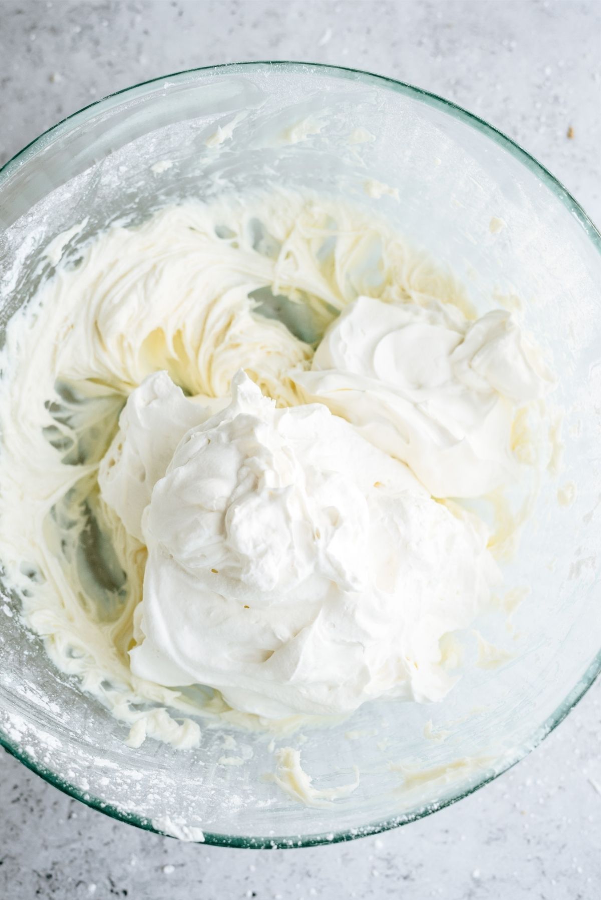 Adding sour cream to the Cream cheese filling in a glass bowl