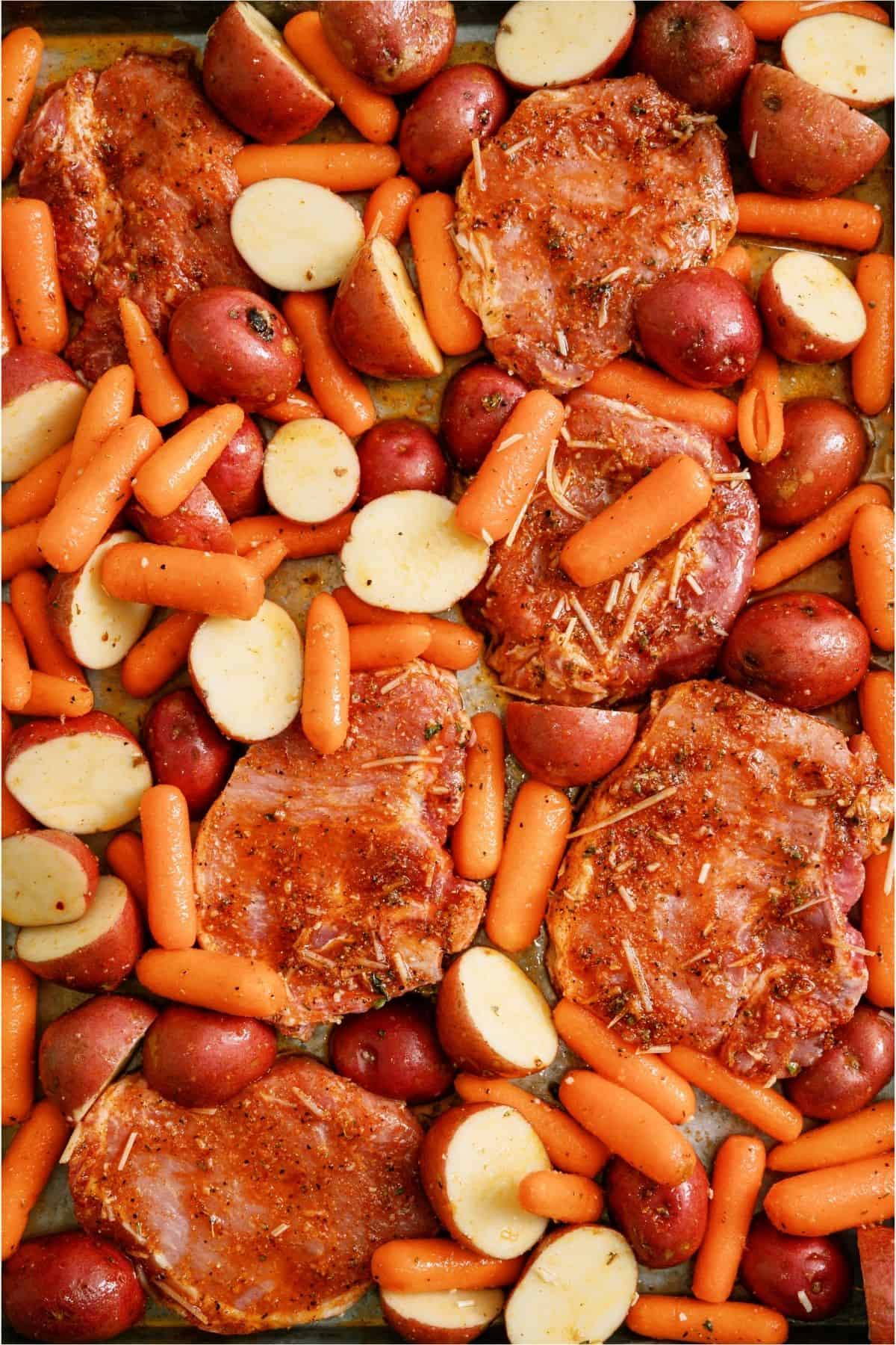 Sheet Pan Italian Pork Chops with potatoes and carrots on a baking sheet.
