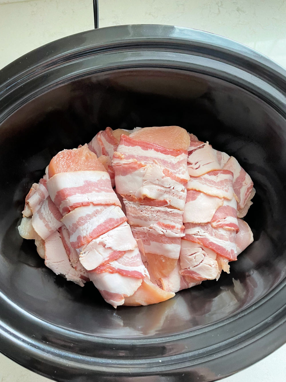 Uncooked Slow Cooker Bacon Wrapped Apple BBQ Chicken in the slow cooker