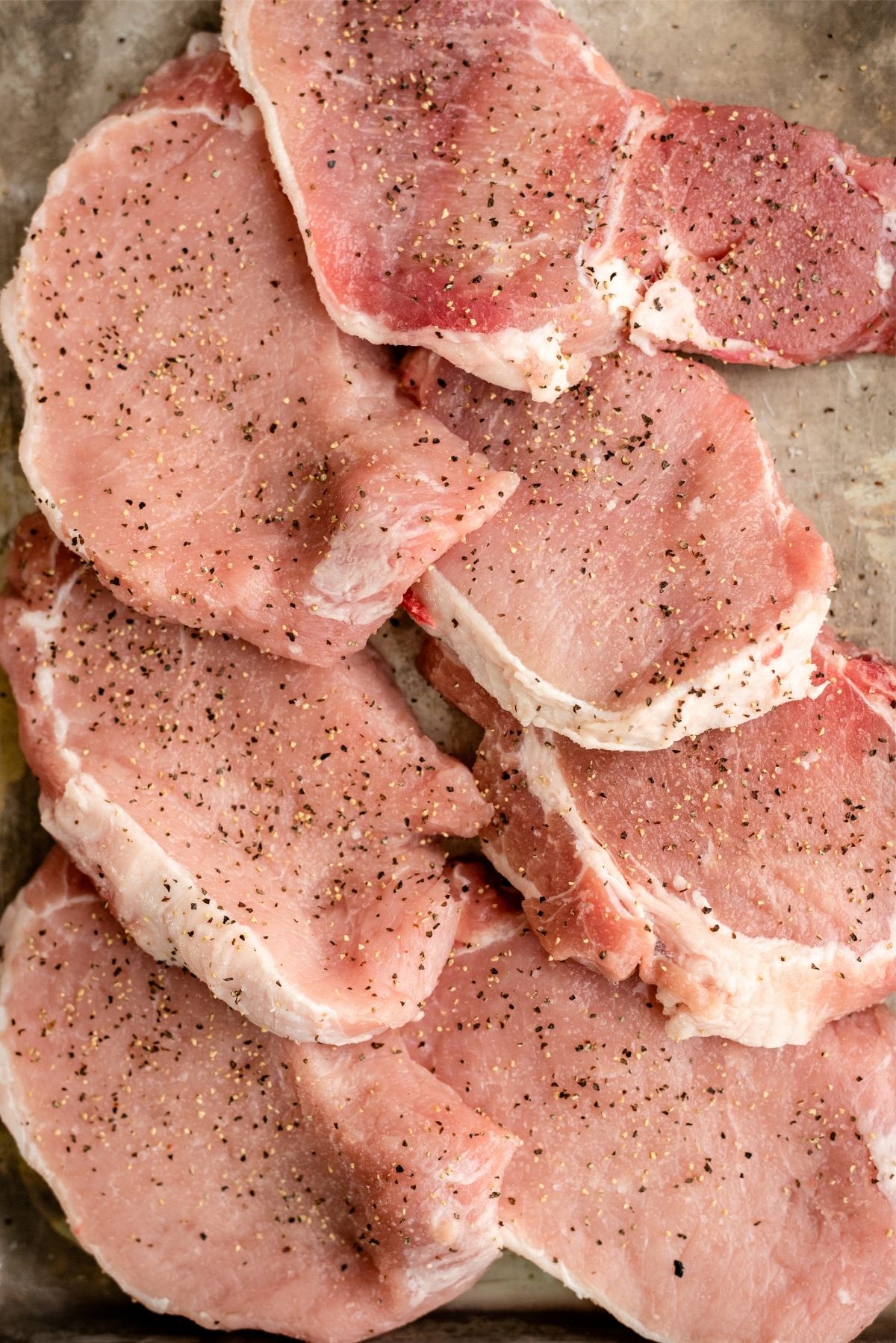 Raw pork chops with salt and pepper on them