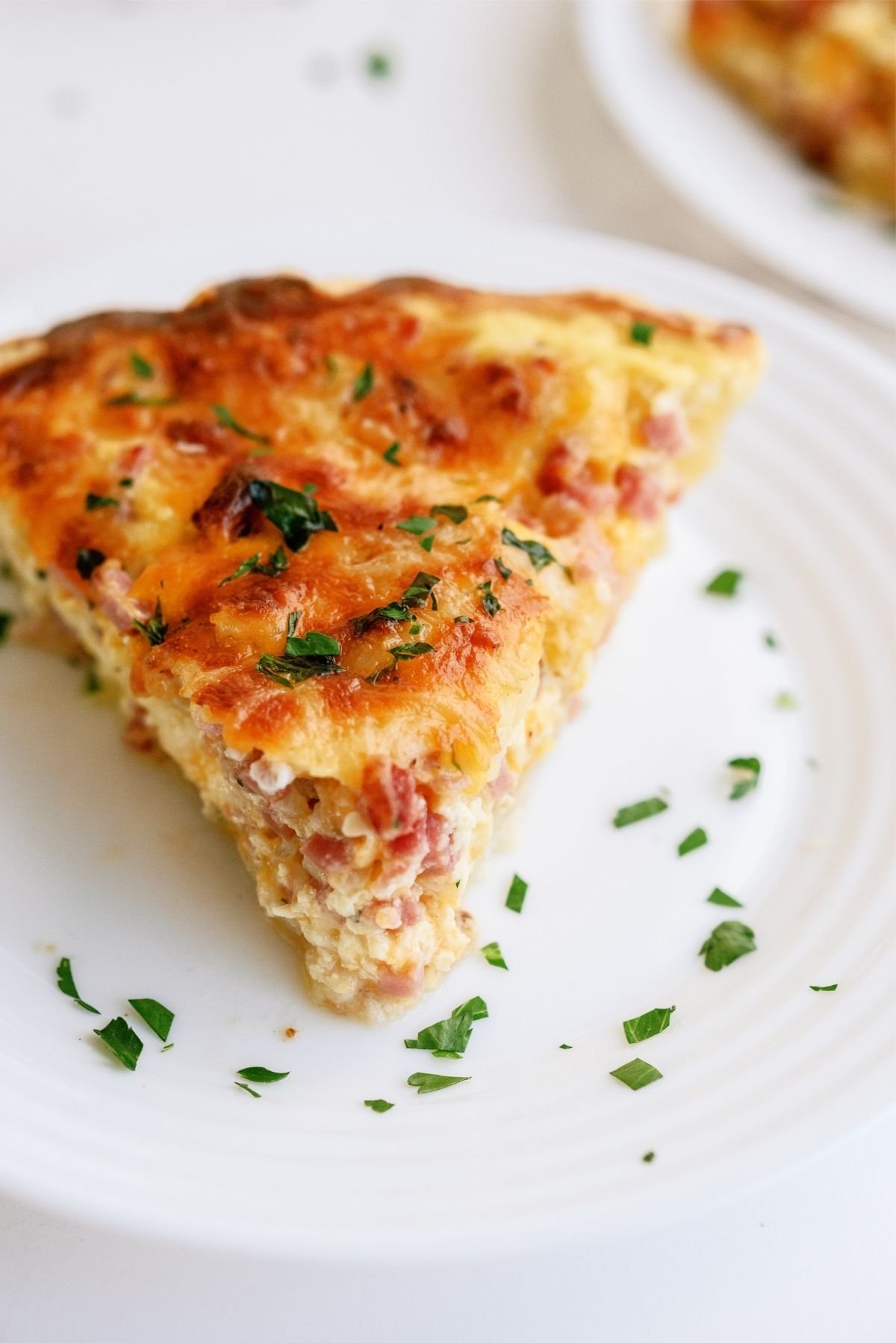 Close up of a slice of Easy Ham and Cheese Quiche on a plate
