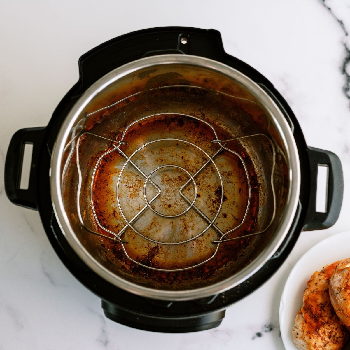 Empty Instant Pot with browned bits on the bottom with trivet inside