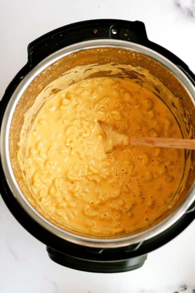 Instant Pot with Mac and Cheese inside and a wooden spoon.