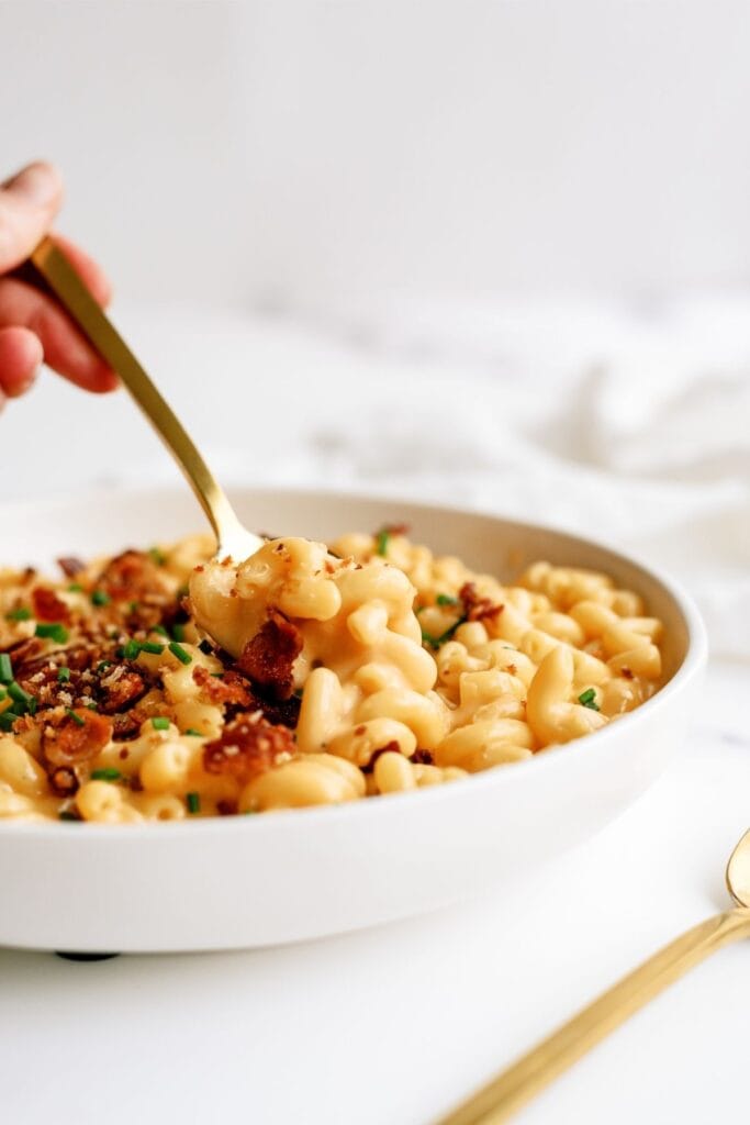 A spoon lifting a bite out of a bowl of Instant Pot Loaded Mac and Cheese.