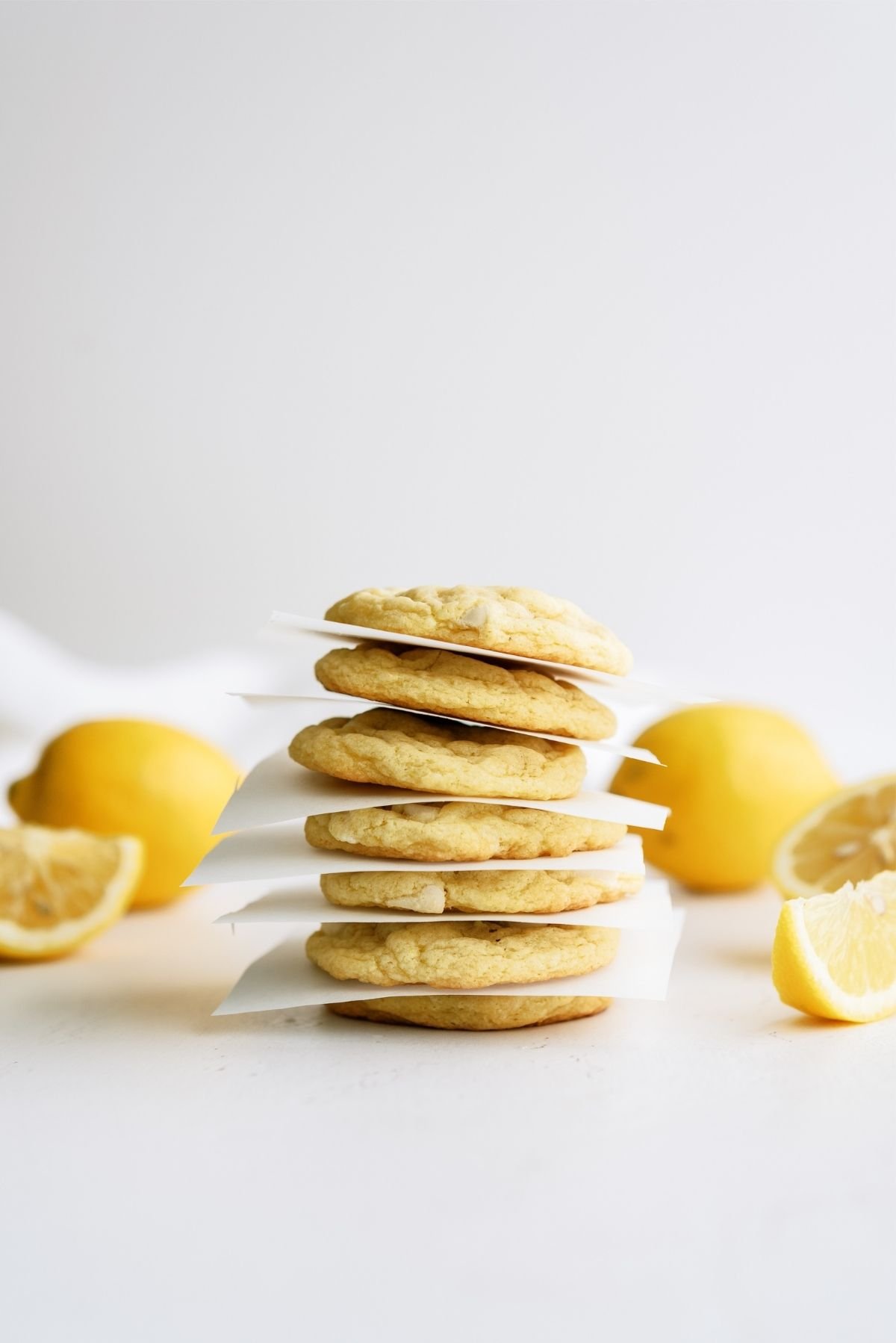 Lemon Cheesecake Pudding Cookies stacked with parchment paper in between them