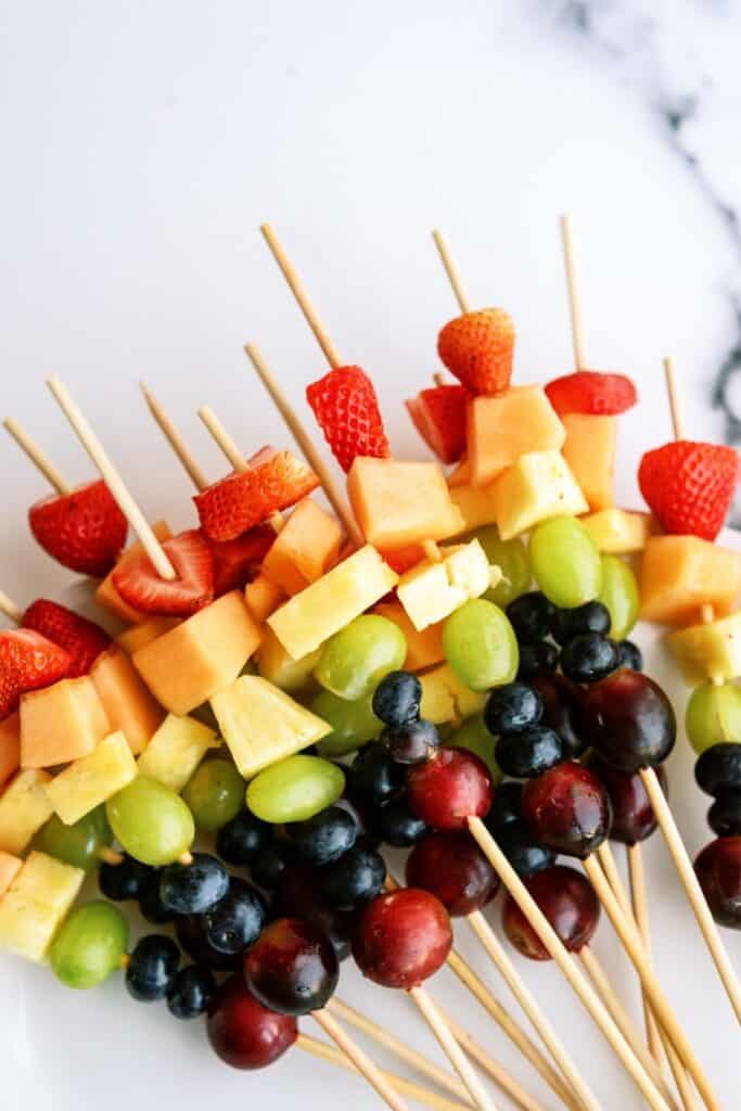 A group of Rainbow Fruit Kabobs on a white background.