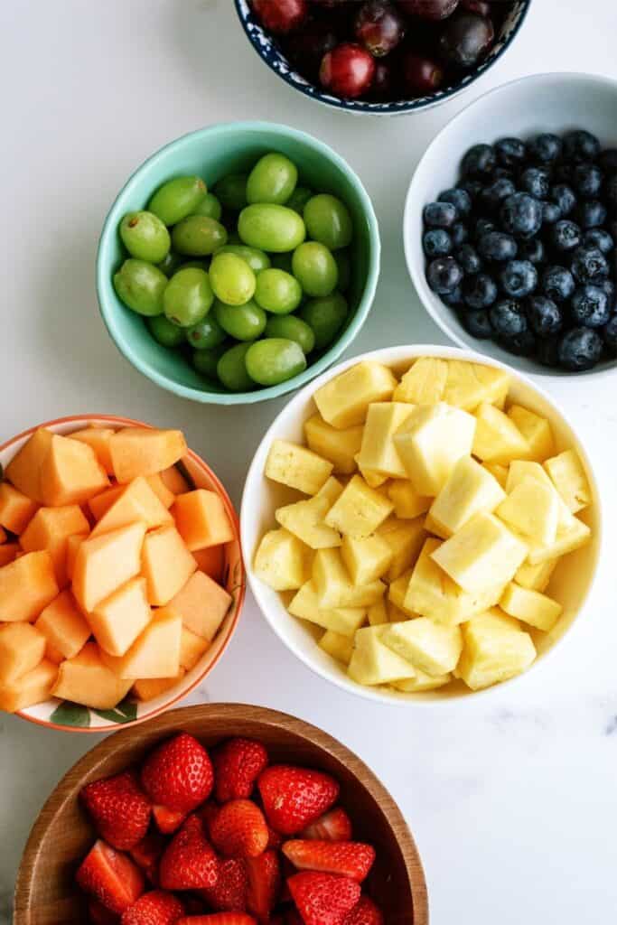 Fruit for kabobs in white bowls.