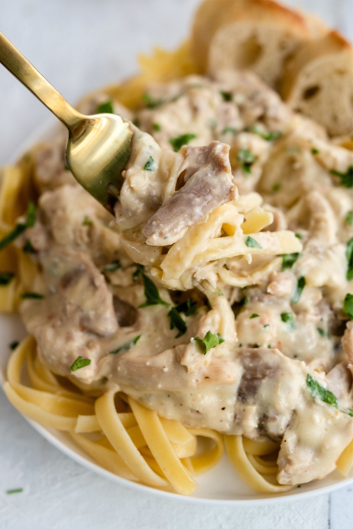 Slow Cooker Creamy Chicken Tetrazzini on a plate with a fork twisted in the pasta