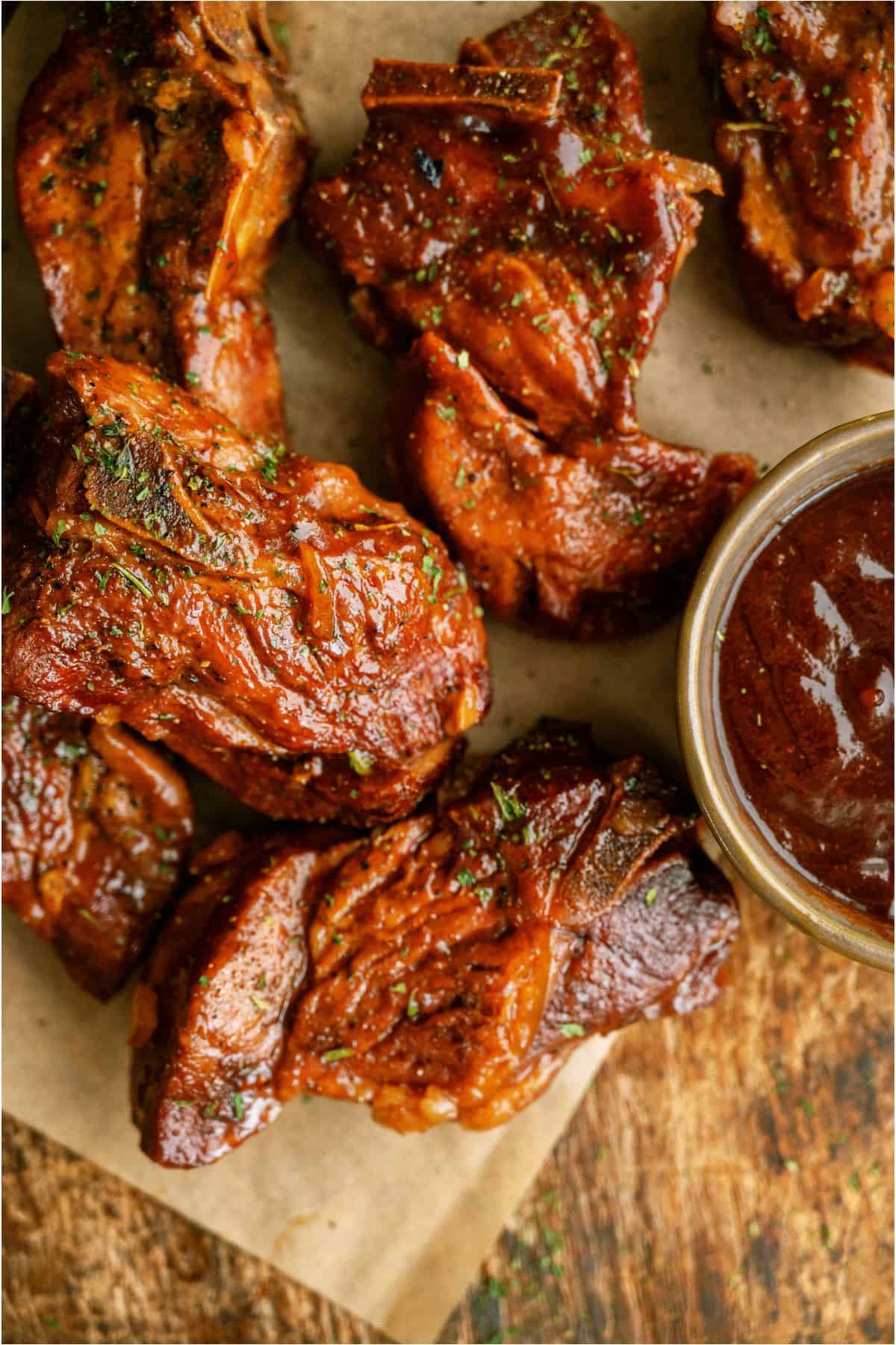 BBQ Slow Cooker Country Style Ribs on parchment paper with a small bowl of BBQ sauce on the side.