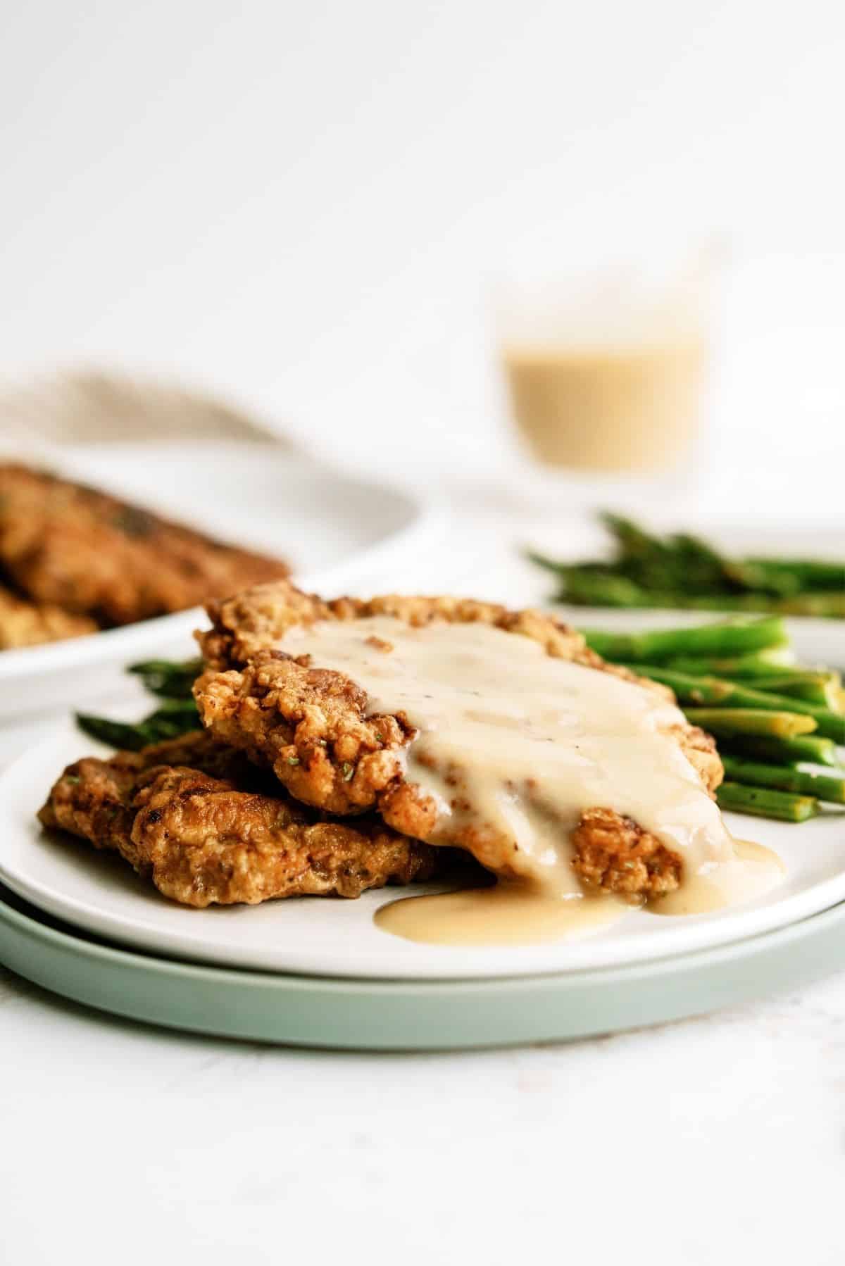 Chicken Fried Steak with Gravy on a plate served with asparagus