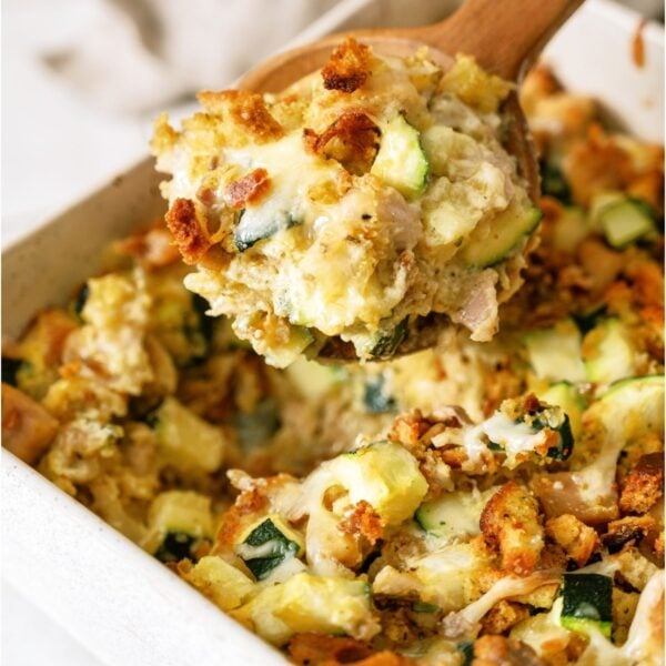 Chicken Zucchini Casserole in a casserole dish with a wooden spoon lifting a scoop of casserole out.