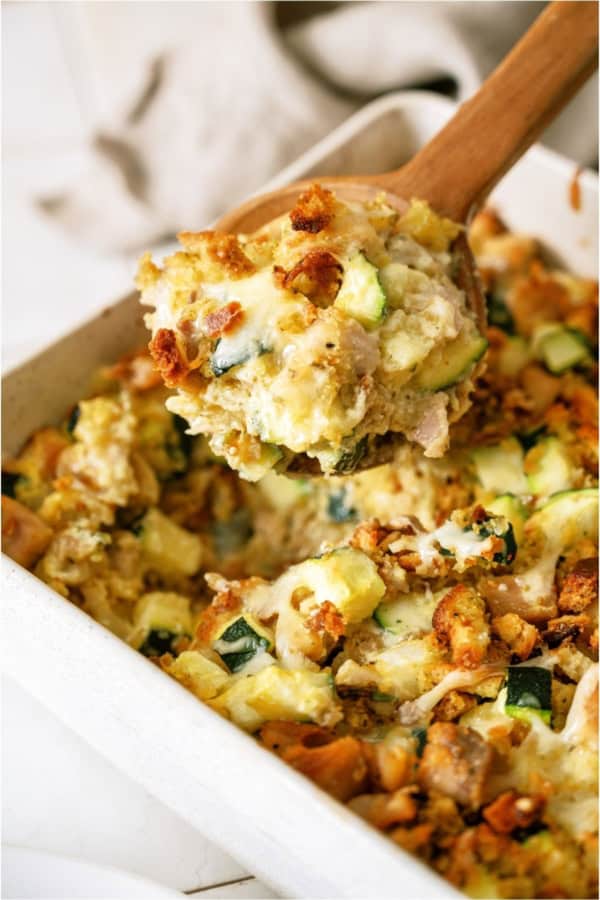 Chicken Zucchini Casserole in a casserole dish with a wooden spoon lifting a scoop of casserole out.