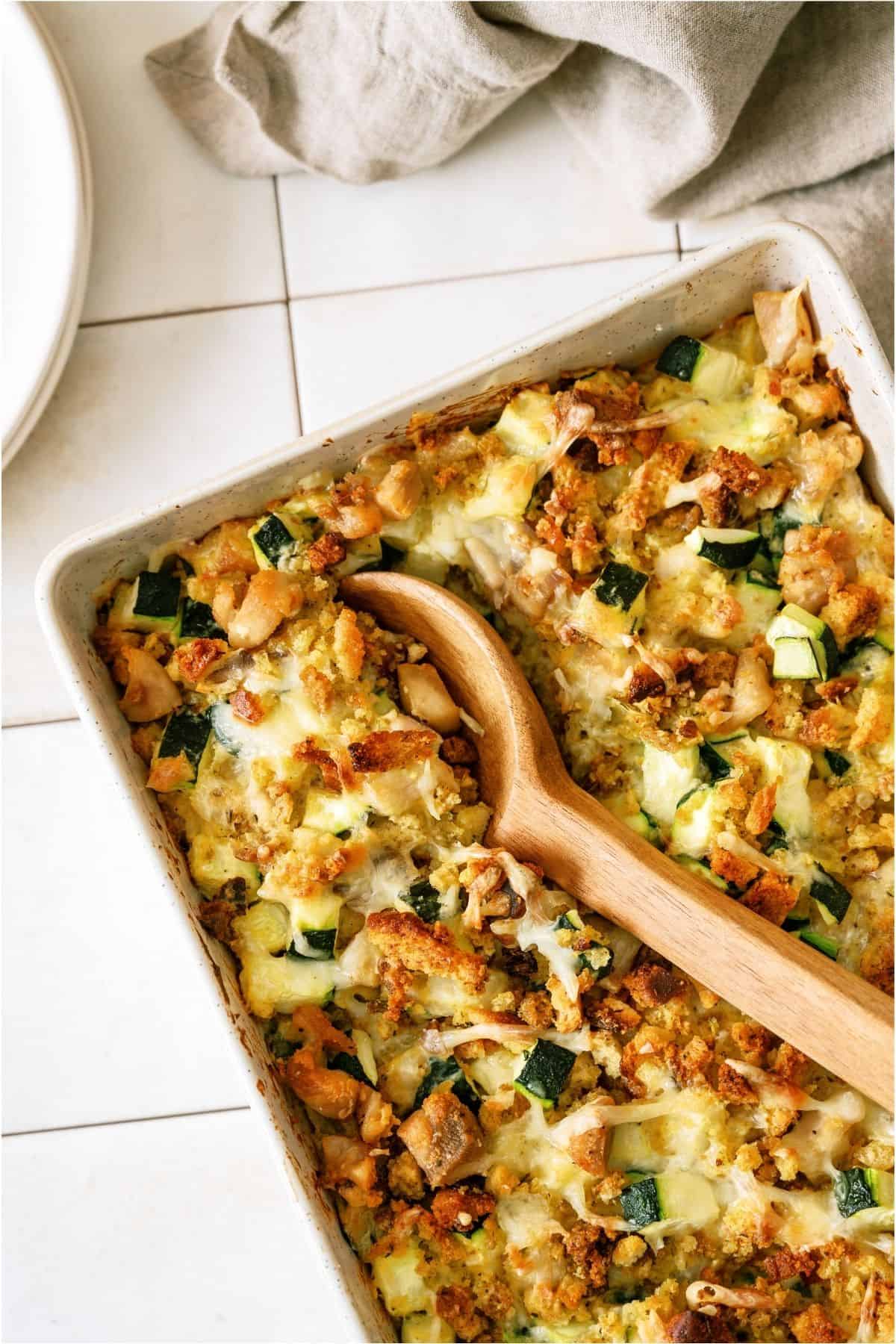 Chicken Zucchini Casserole in casserole dish with a wooden spoon scooping out a serving.