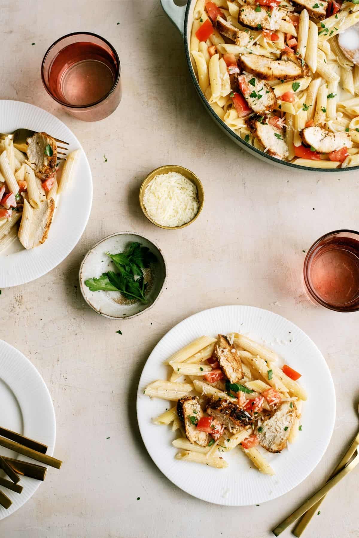 A pan of Chili’s Copycat Cajun Chicken Pasta and two servings on plates