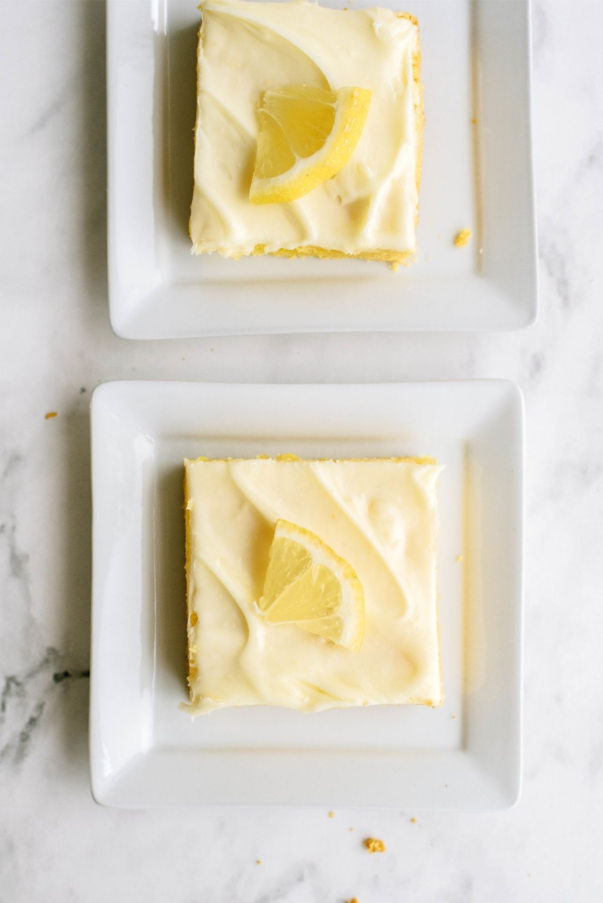 Two slices of Frosted Gooey Lemon Bars on plates