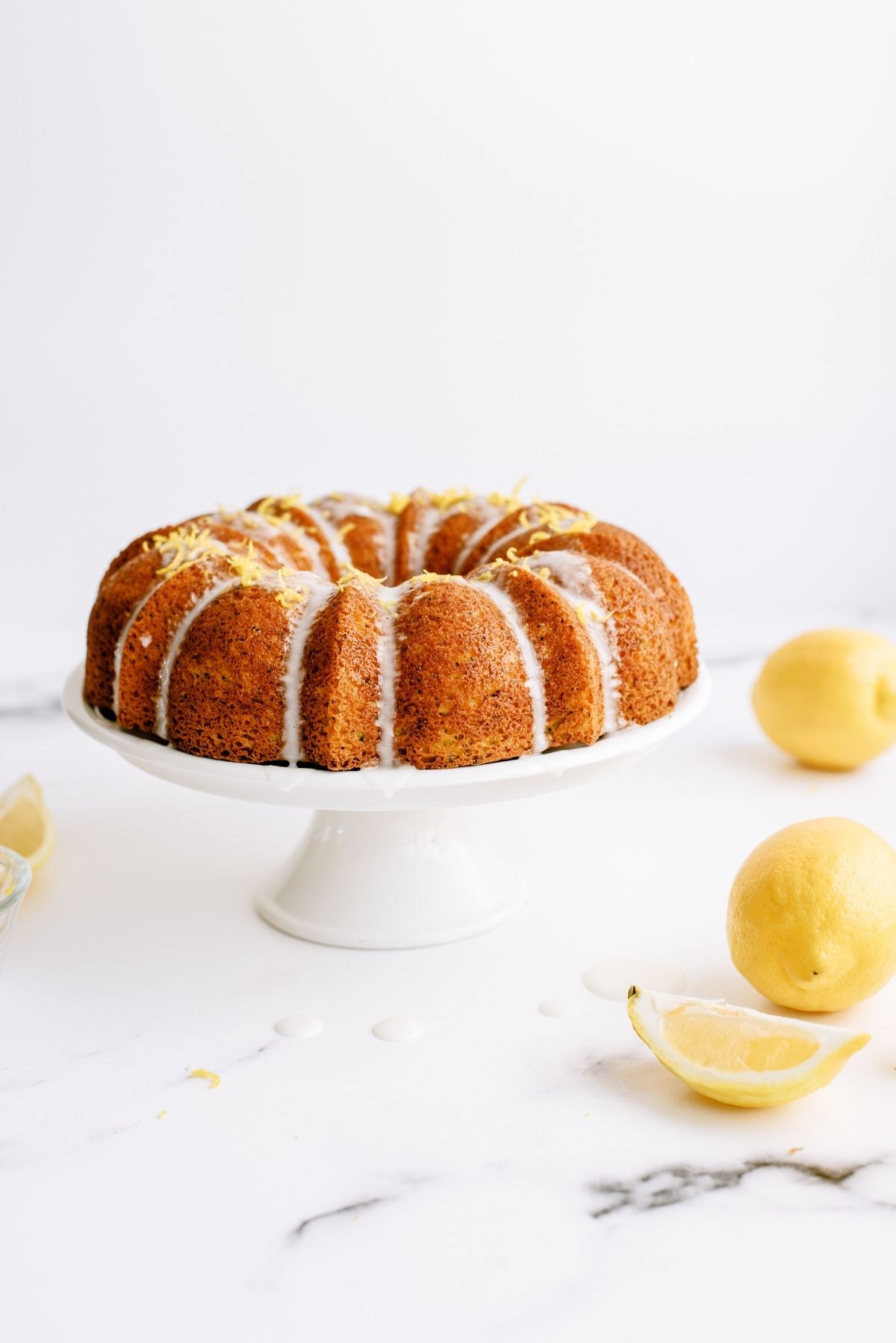 Lemon Poppy Seed Bundt Cake on a cake stand with lemons