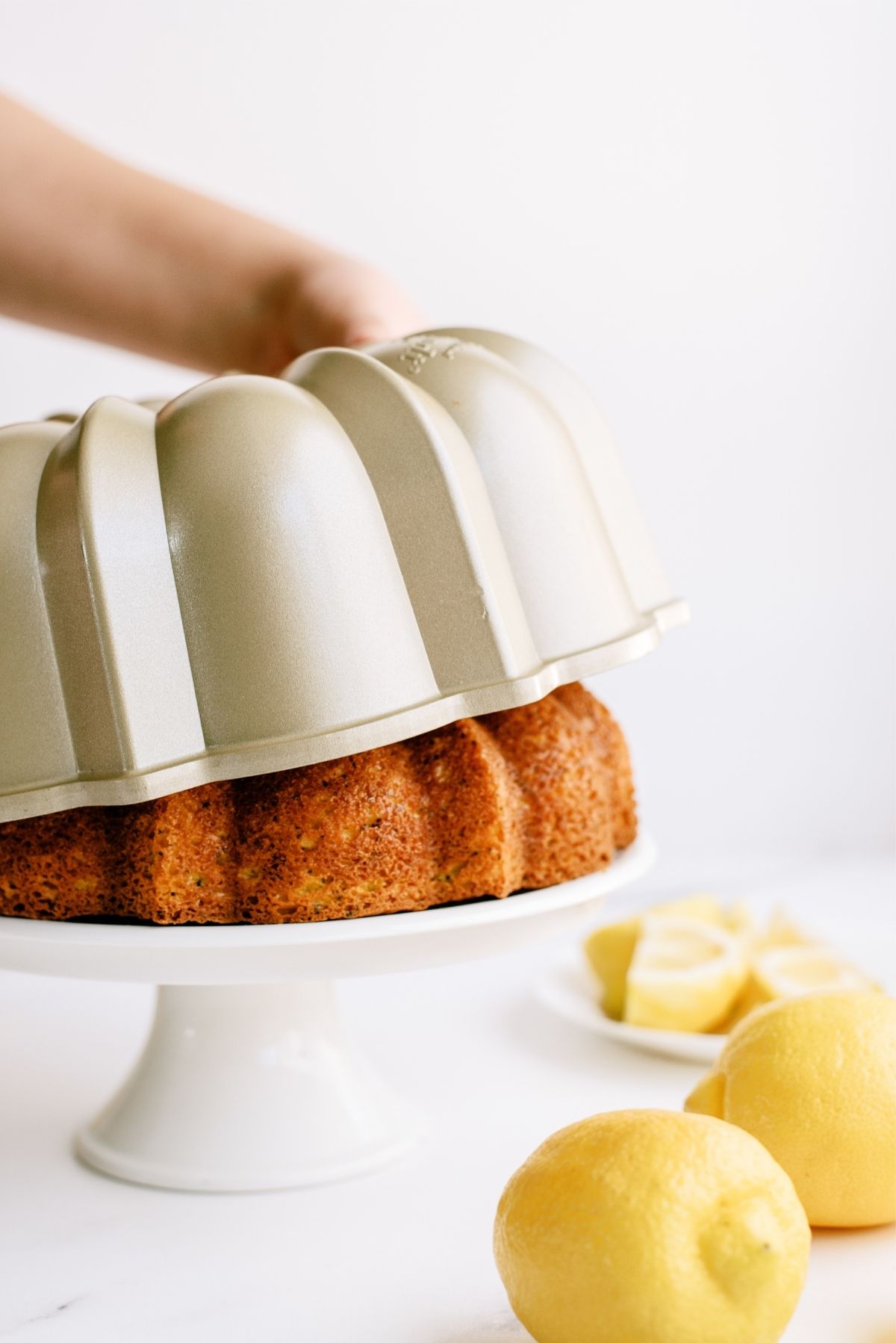 Lemon Poppy Seed Bundt Cake coming out of the Bundt pan onto a cake stand