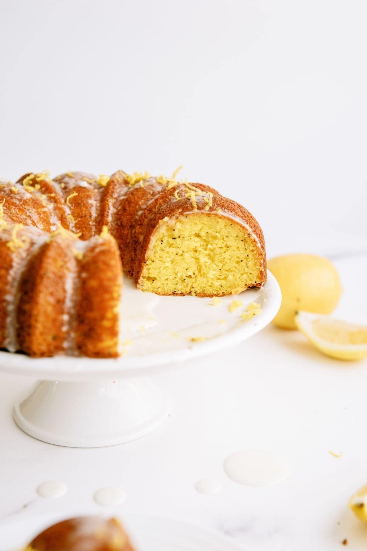 Slice missing out of Lemon Poppy Seed Bundt Cake on cake stand