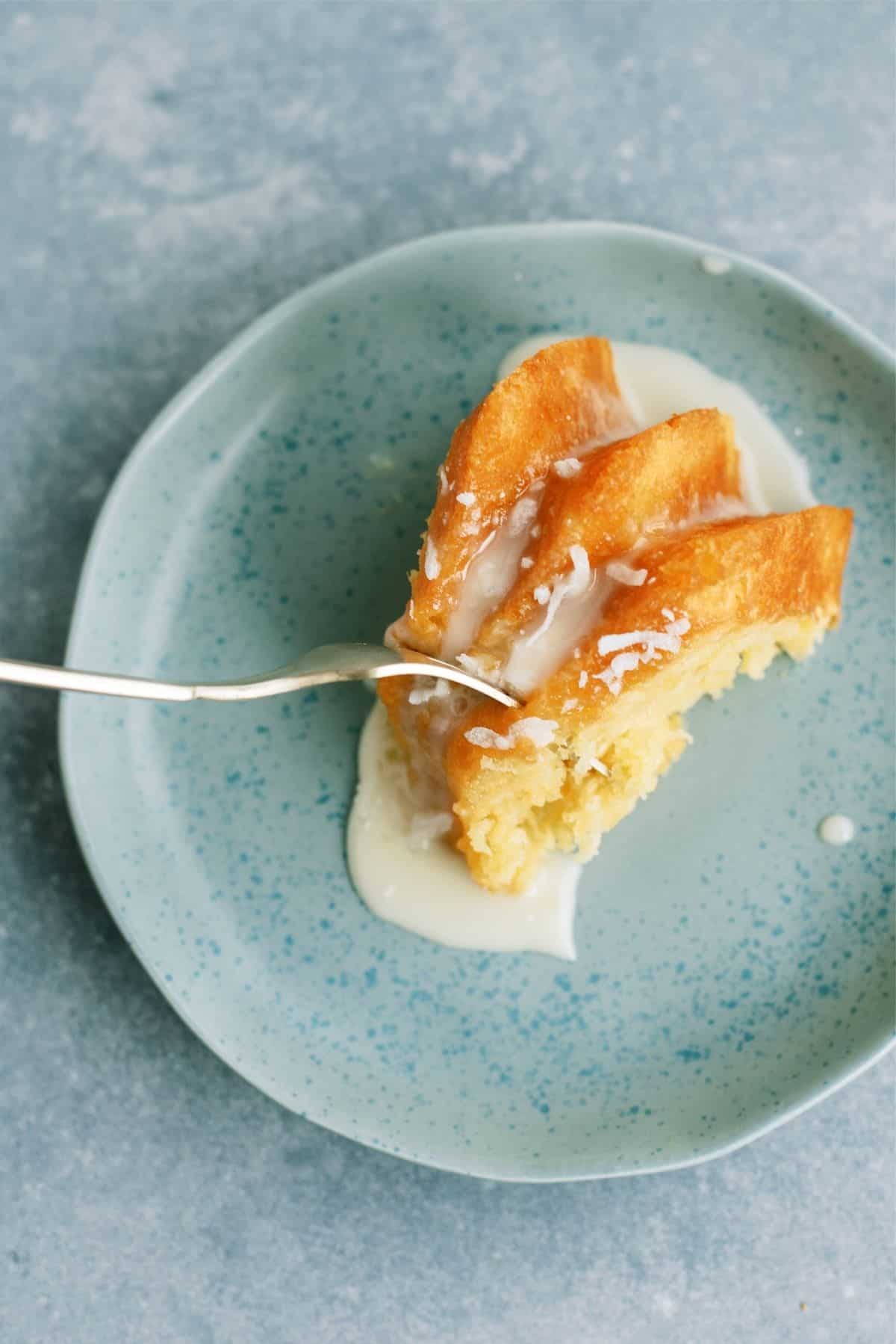 A fork slicing off a bite of Pineapple Coconut Bundt Cake on a plate