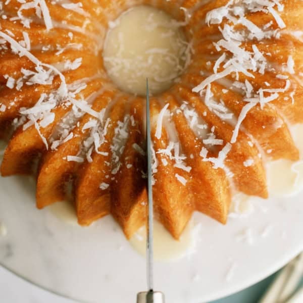 Top view of a knife cutting a slice of Pineapple Coconut Bundt Cake.