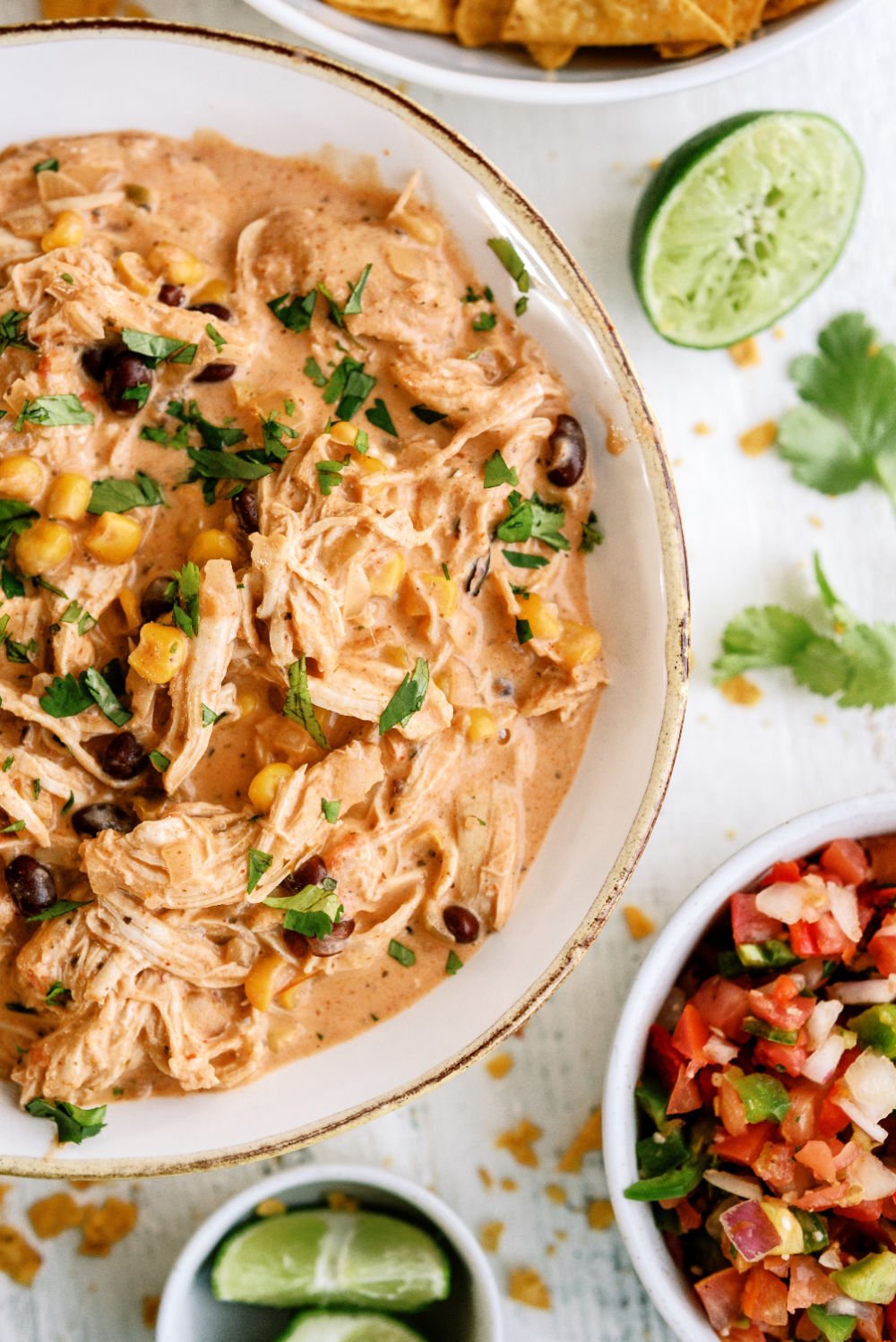 Slow Cooker Creamy Fiesta Chicken in a bowl surrounded by toppings