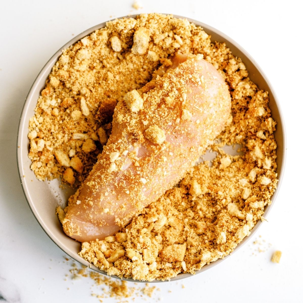 Dipping raw chicken breast in crouton crumbs