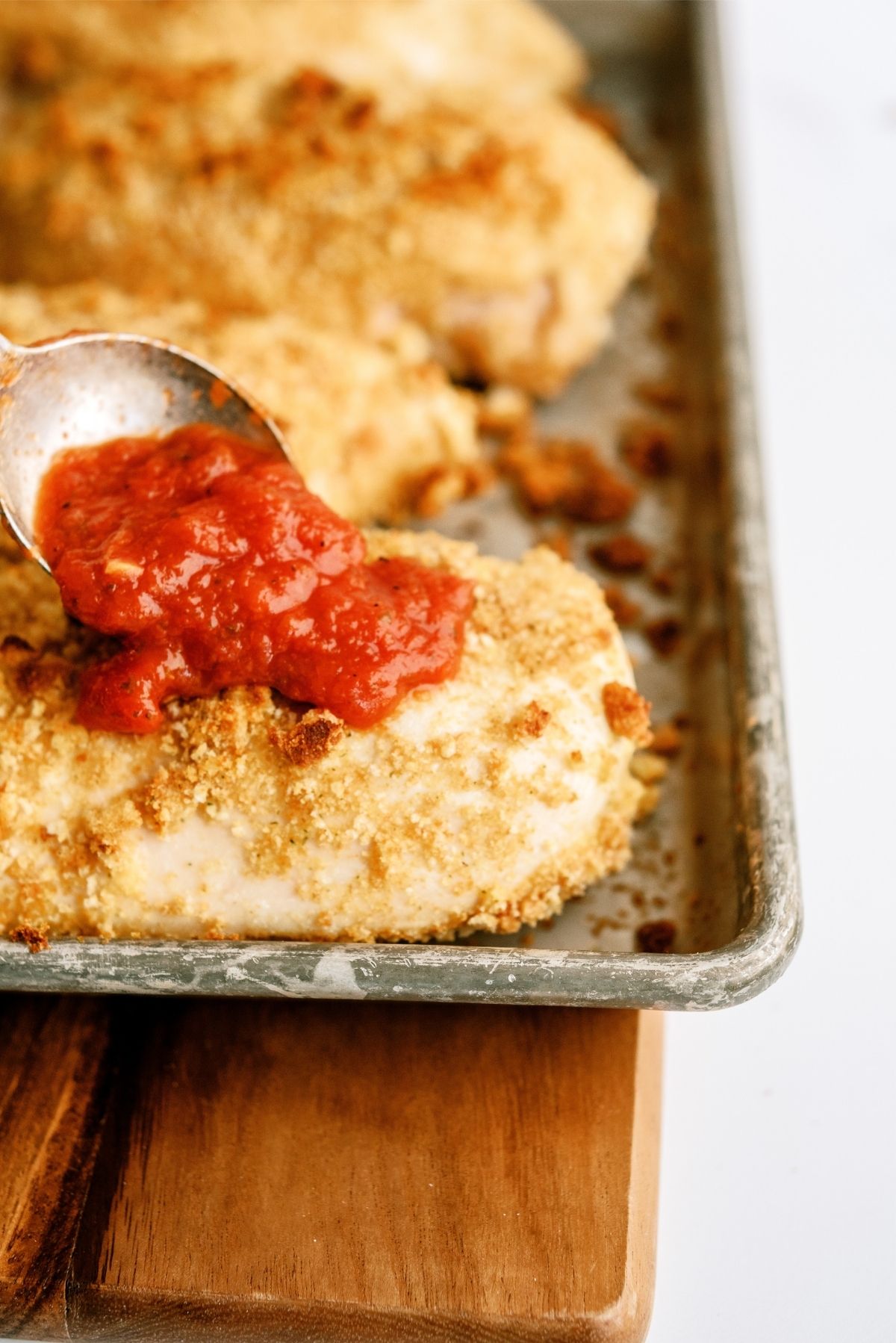Adding sauce on top of baked parmesan chicken