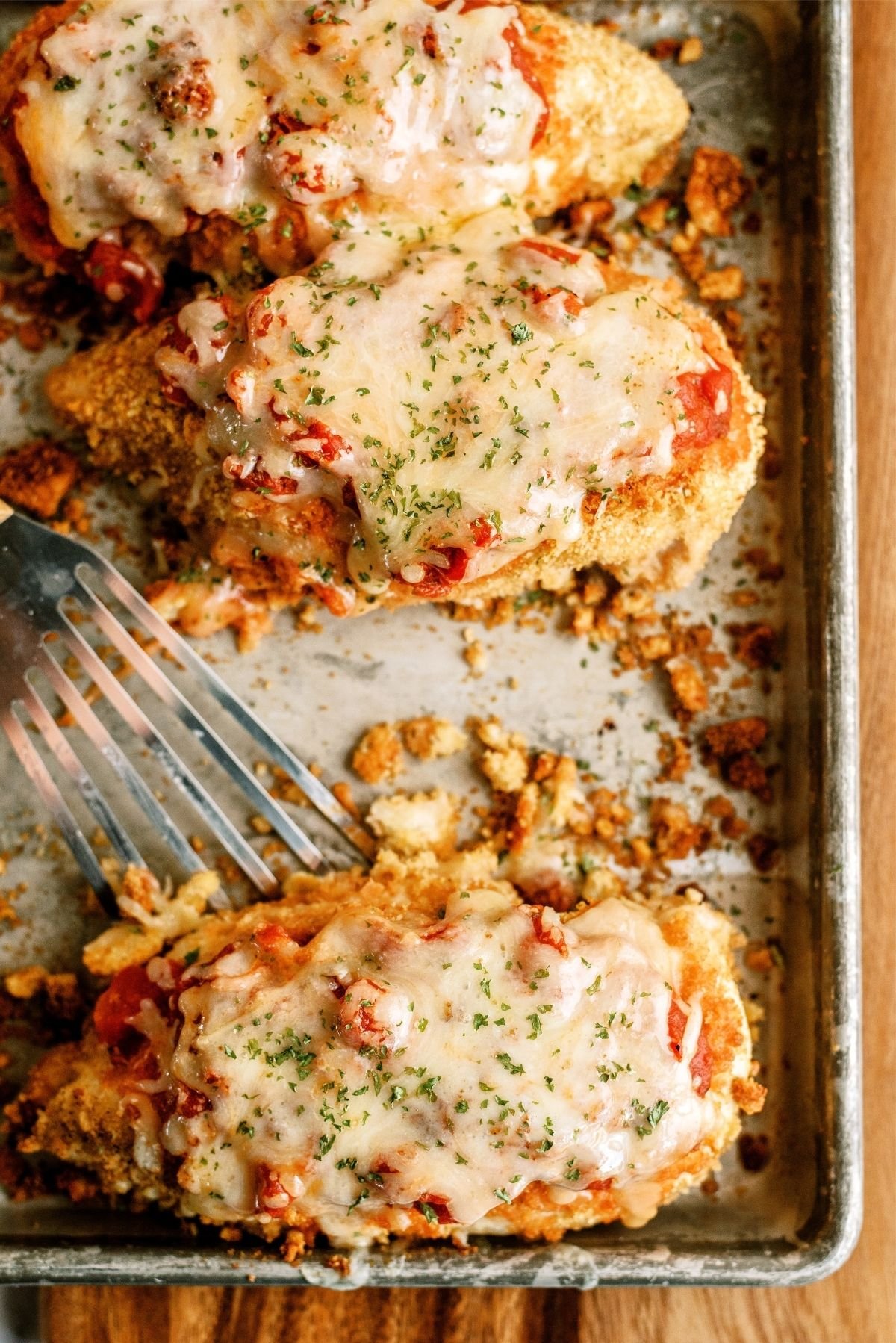 Baked Crispy Chicken Parmesan on a baking sheet with a serving spatula