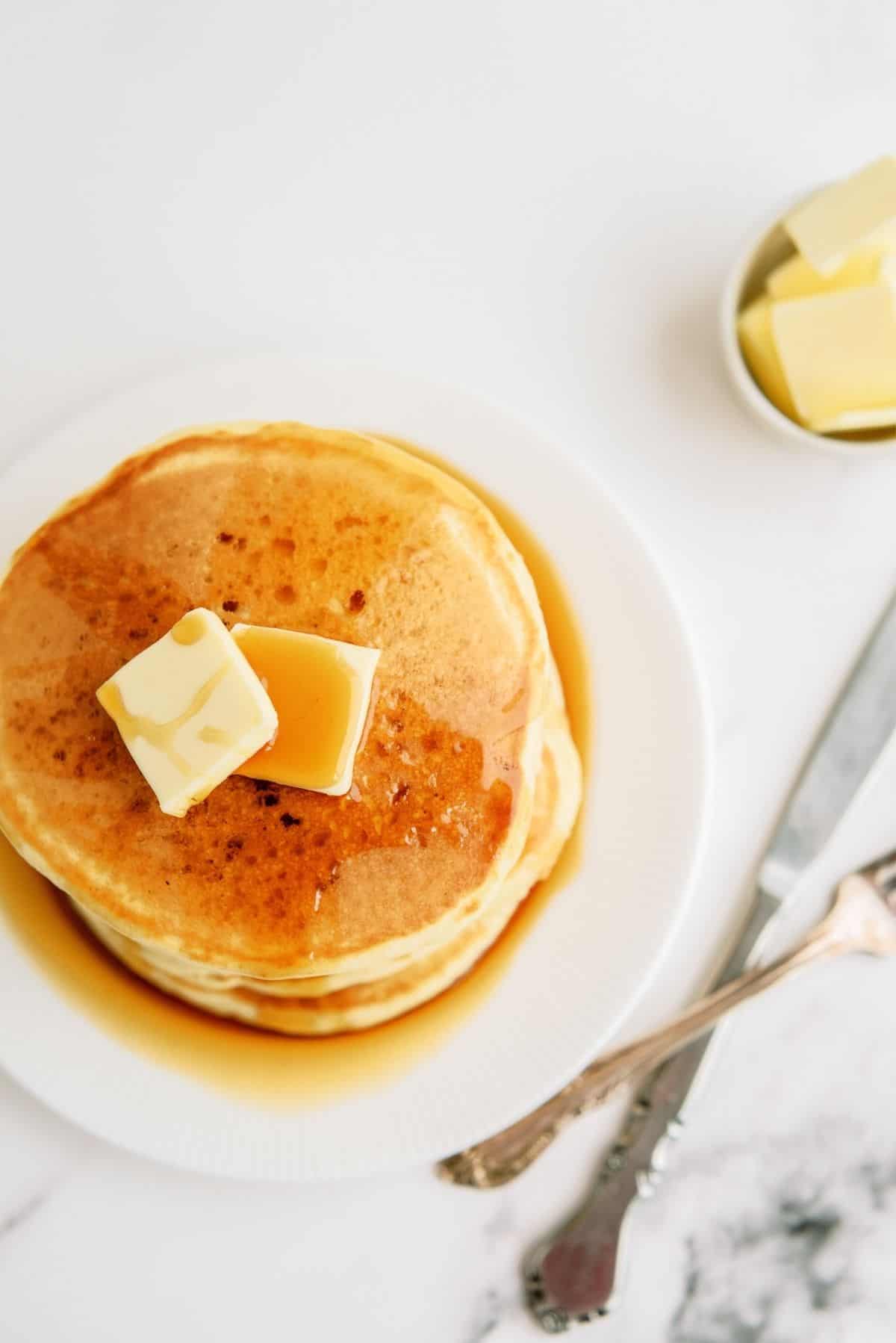 Stack of Cracker Barrel Buttermilk Pancakes on a plate with butter and syrup