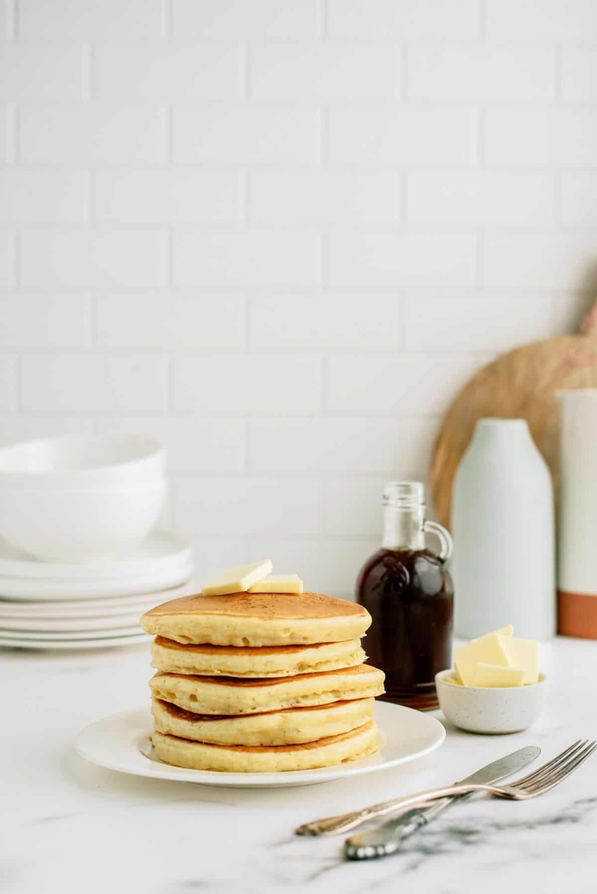 Stack of Cracker Barrel Buttermilk Pancakes on a plate with butter and syrup on the side