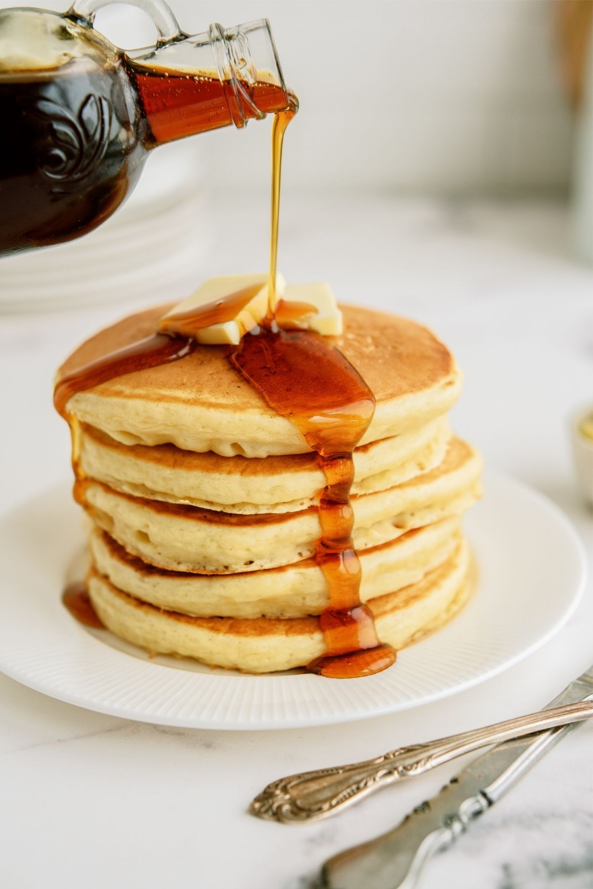 Pouring syrup on top of stack of Cracker Barrel Buttermilk Pancakes