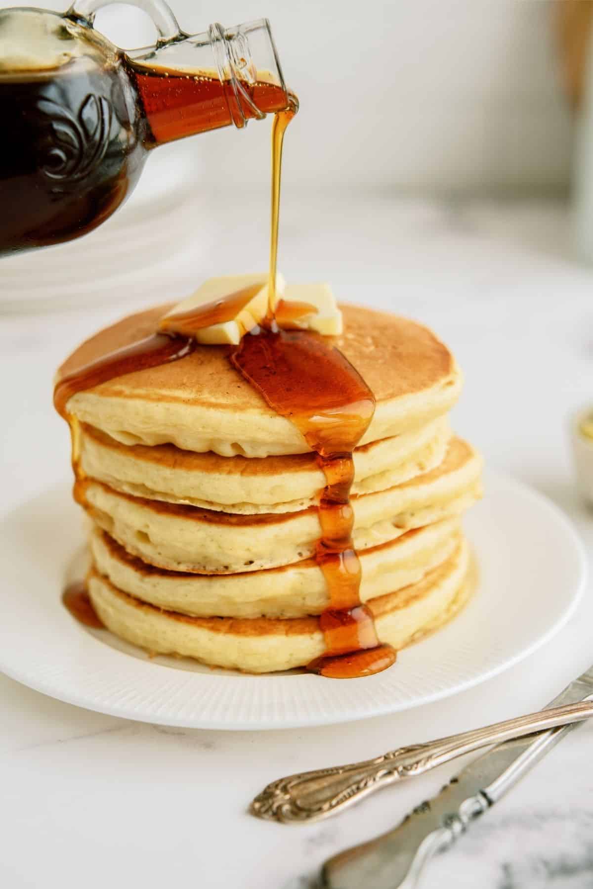 Pouring syrup on top of stack of Cracker Barrel Buttermilk Pancakes