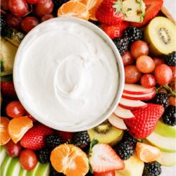 A platter of sliced fruit with a small bowl of Easy Cream Cheese Fruit Dip in the center of the platter.