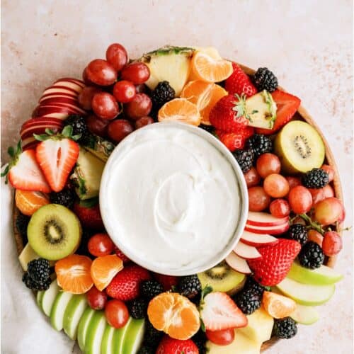 Top view of a platter of sliced fruit with a small bowl of Easy Cream Cheese Fruit Dip in the center.