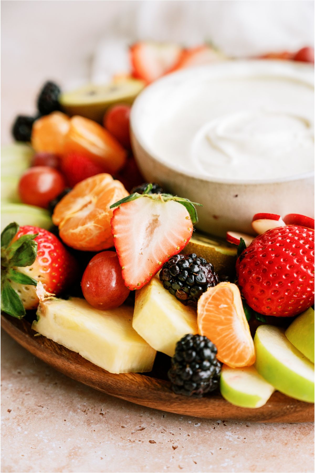 Sliced fruit on a tray with a small bowl of Easy Cream Cheese Fruit Dip.