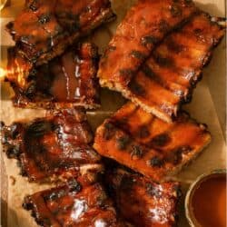 Easy Smoked Bbq ribs on a cutting board with sauce and dipping sauce.
