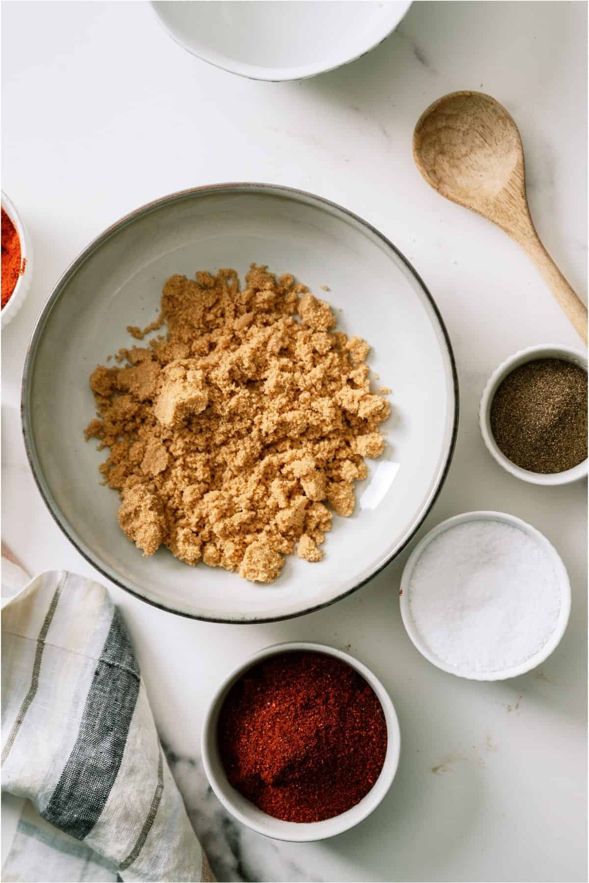 Brown sugar in a bowl with the remaining ingredients for the rub in small bowls to the side.