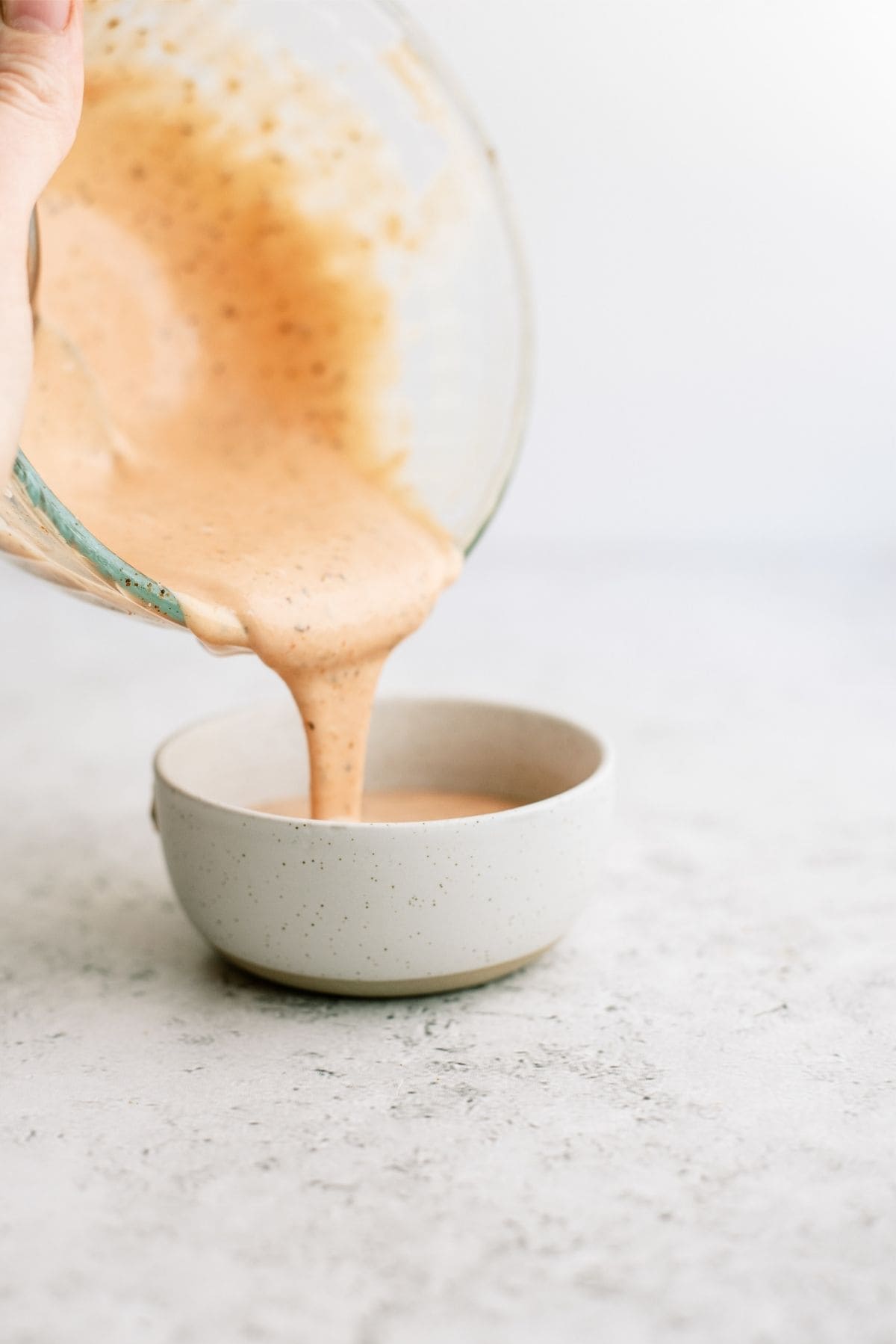 A bowl of Raising Cane’s Chicken Sauce being poured into a small bowl